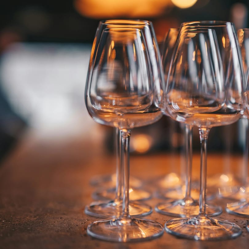 Several empty wine glasses with warm lighting reflecting on their surfaces, ready for service.